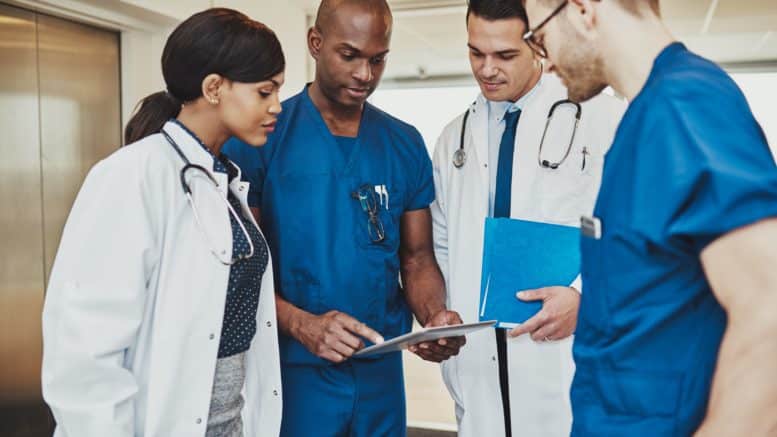 Equipe multiprofissional de saúde analisando checklist de auditoria CCIH e protocolos de prevenção de infecção hospitalar.